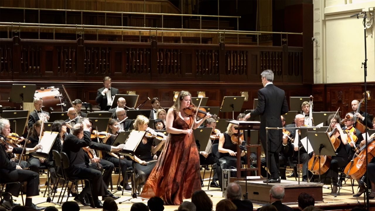 a woman playing violin with an orchestra